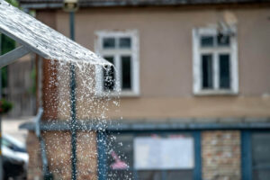 Water spout cascading from a roof, creating a stream of water falling to the ground below.
